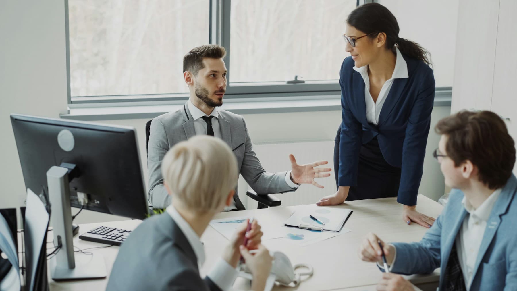 Colleagues in discussion around a meeting table in a bright office