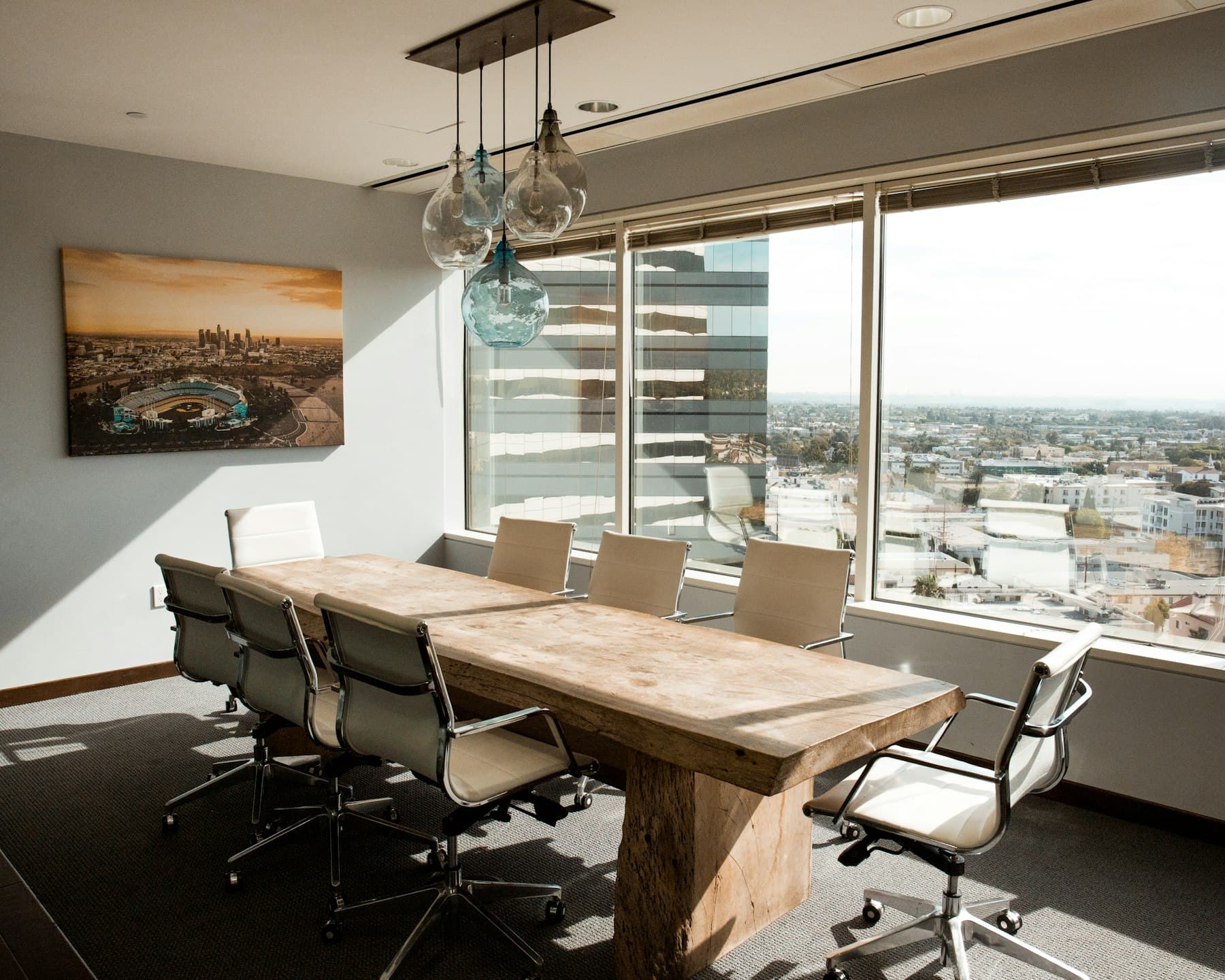 A meeting room with a long timber table and wide windows overlooking the city